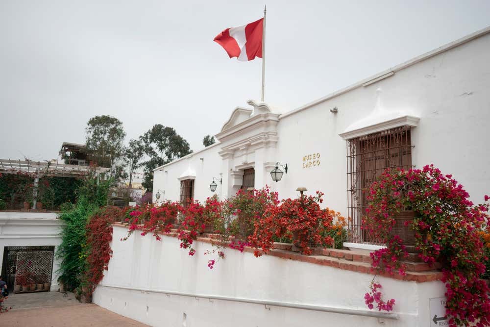 La fachada del Museo Larco con la bandera de Perú y buganvillas decorativas