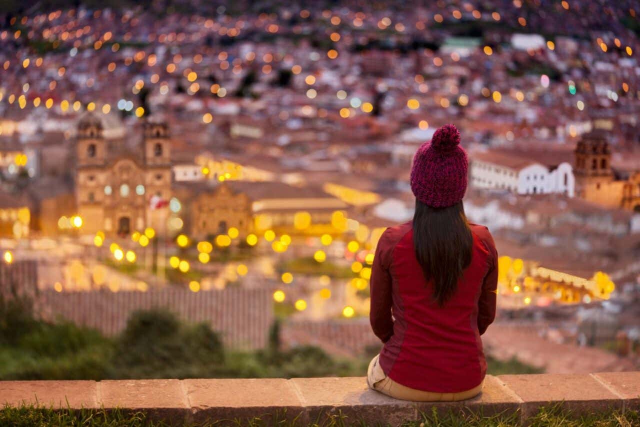 Una mujer sentada admirando el centro de Cusco desde el mirador de San Cristóbal
