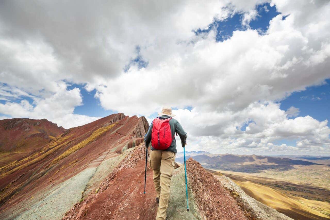 Un hombre realiza senderismo en una montaña de colores en un día soleado