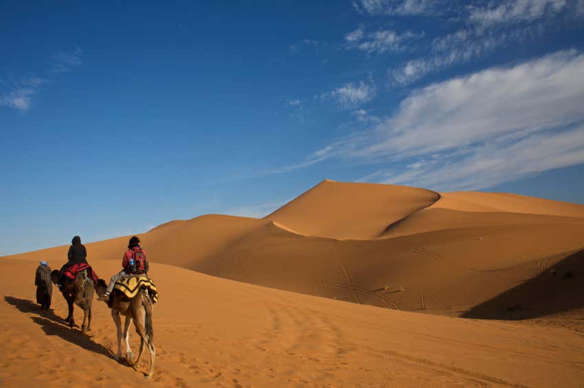 Deux voyageurs à dos de chameau dans le désert marocain de Merzouga