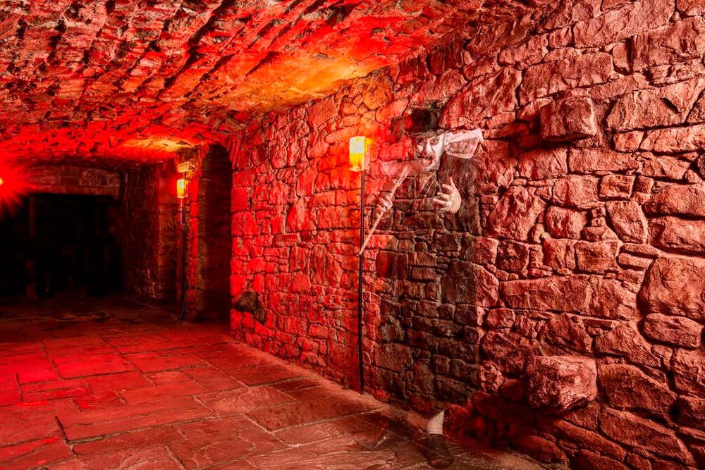 Subterráneos de Edimburgo al caer la noche, iluminados con luz roja y tenue. Una escapada perfecta para el Puente de Todos los Santos.