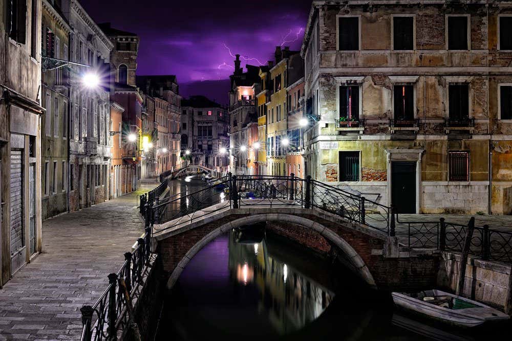 Una estampa de los canales de Venecia al anochecer con una tormenta de fondo