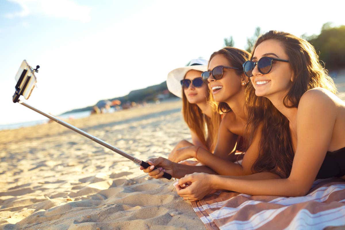 Tres mujeres jóvenes y caucásicas haciéndose un selfie en una playa italiana durante el Ferragosto