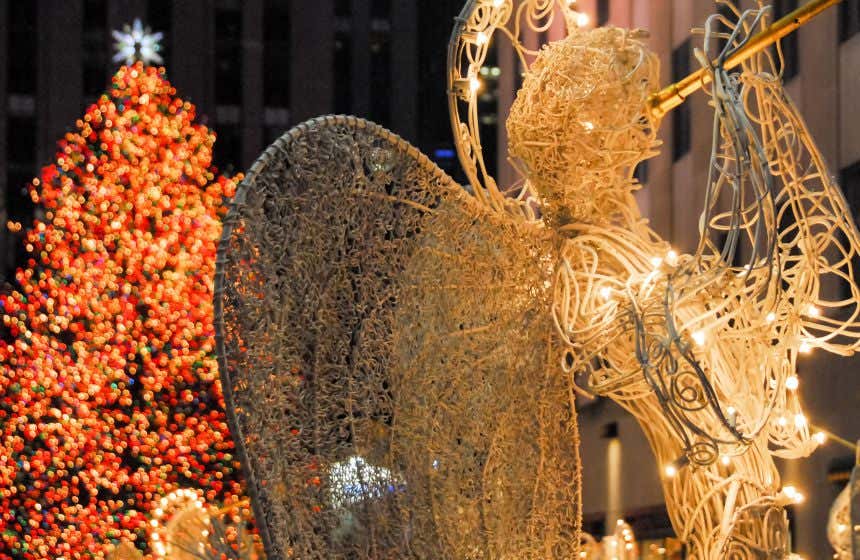 Escultura de un ángel con trompeta frente al árbol de Navidad del edificio Rockefeller Center de Nueva York