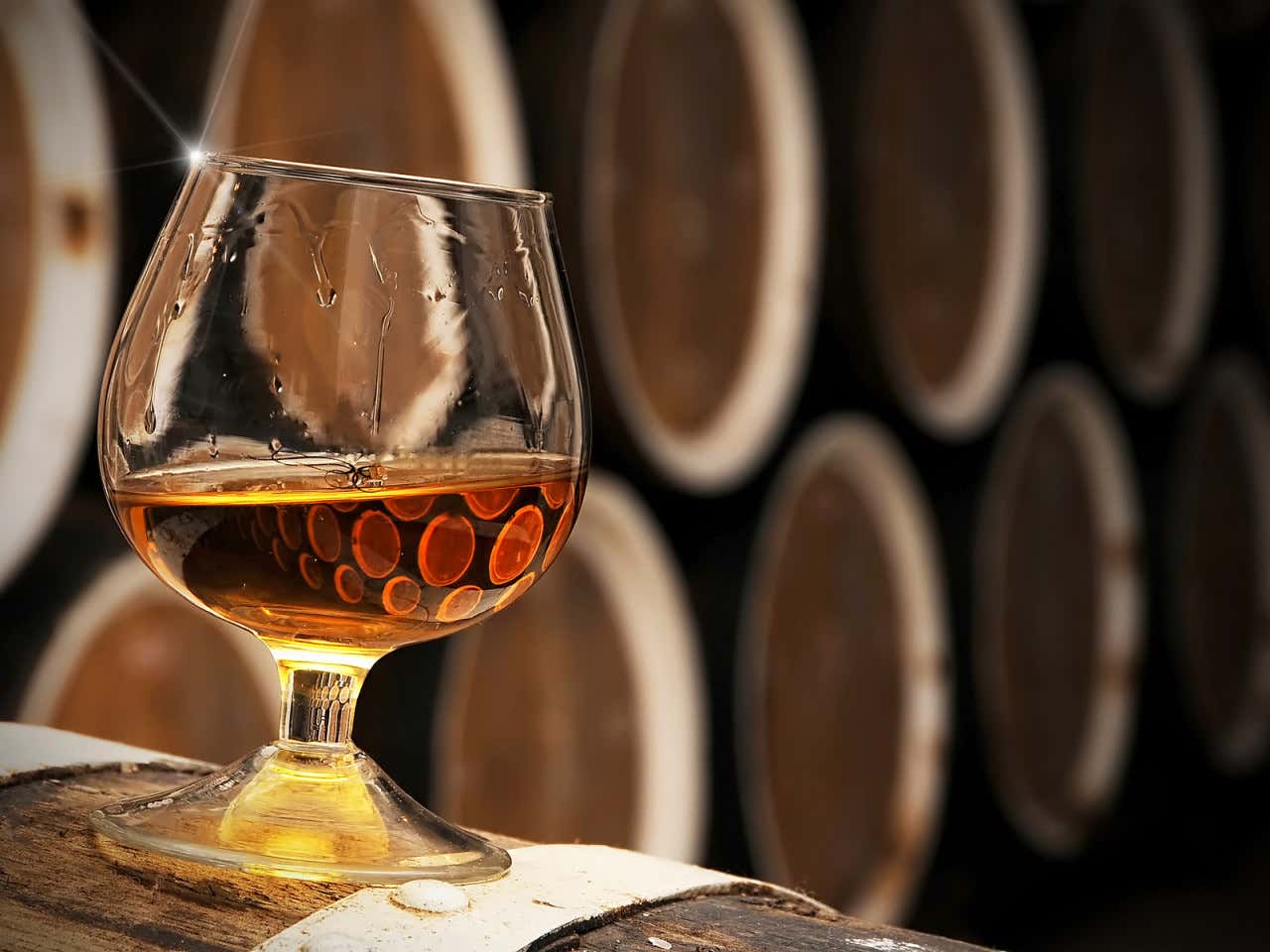Un baso de brandy con las barricas detrás en las Bodegas 501