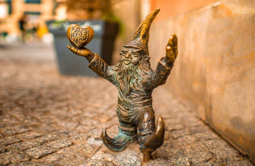 Uma escultura de metal de um duende em uma rua empedrada