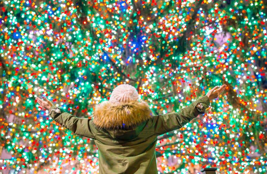 Una persona con gorro y abrigo de invierno observa las luces de Navidad del árbol más famoso de Nueva York, en Rockefeller Center.