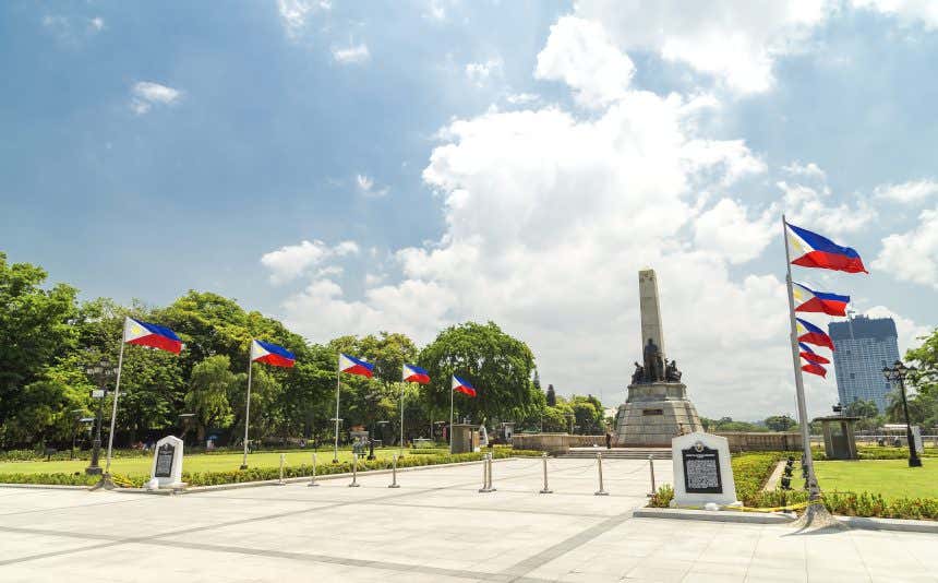 Monumento da Independência na praça do Parque Rizal de Manila com diversas bandeiras nacionais