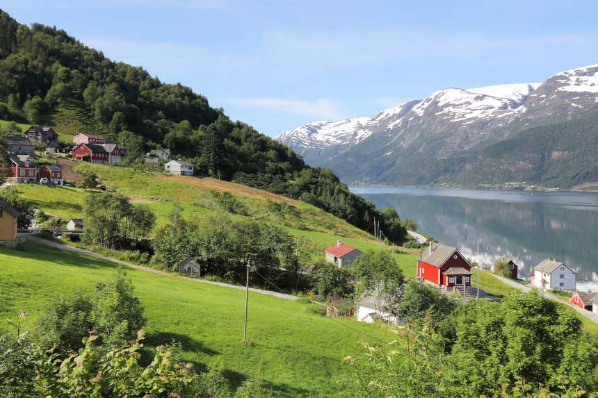 Dia de sol em um fiorde norueguês com as casas de madeira