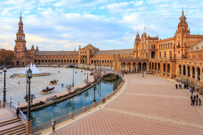 Panorámica de la Plaza de España de Sevilla bordeada por un canal y con pórticos a los laterales.