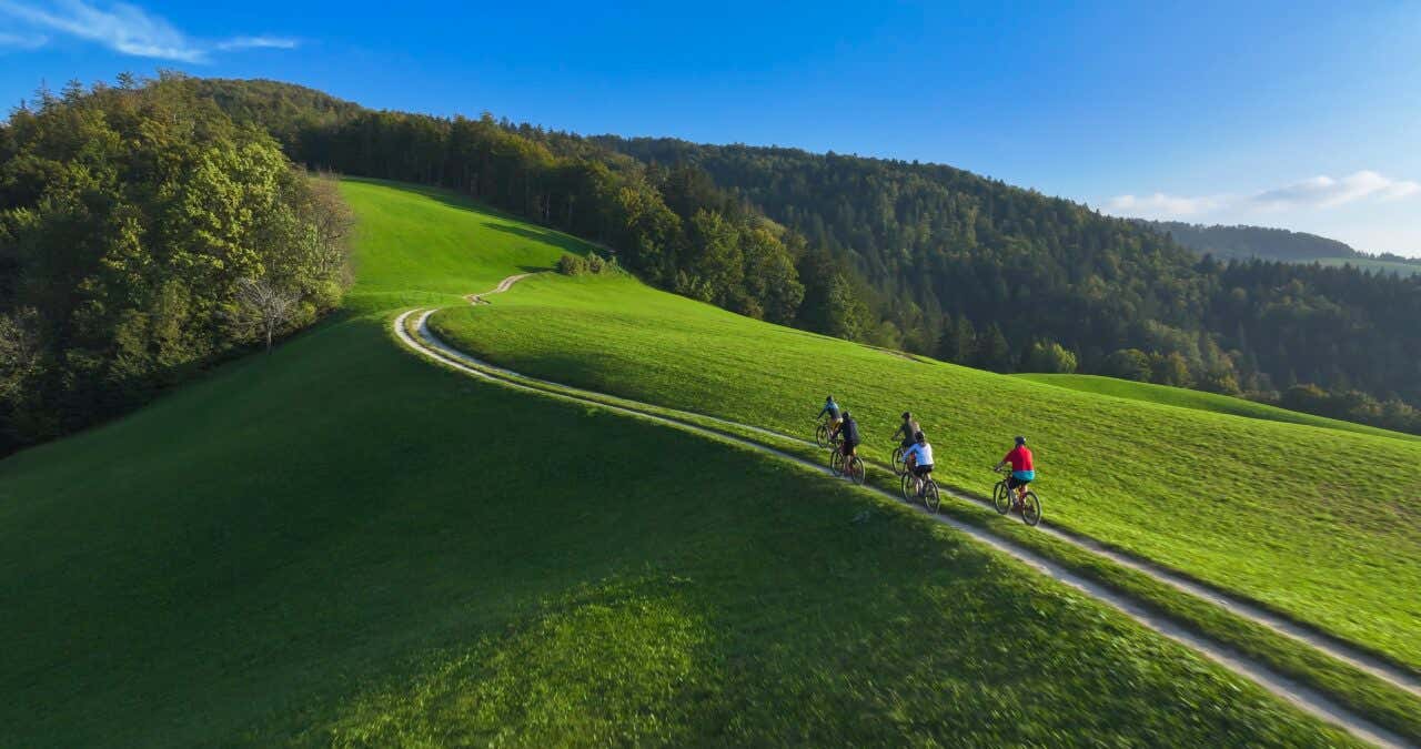 Vue aérienne d'un groupe de personnes faisant du vélo sur un chemin de terre sur une coline verdoyante