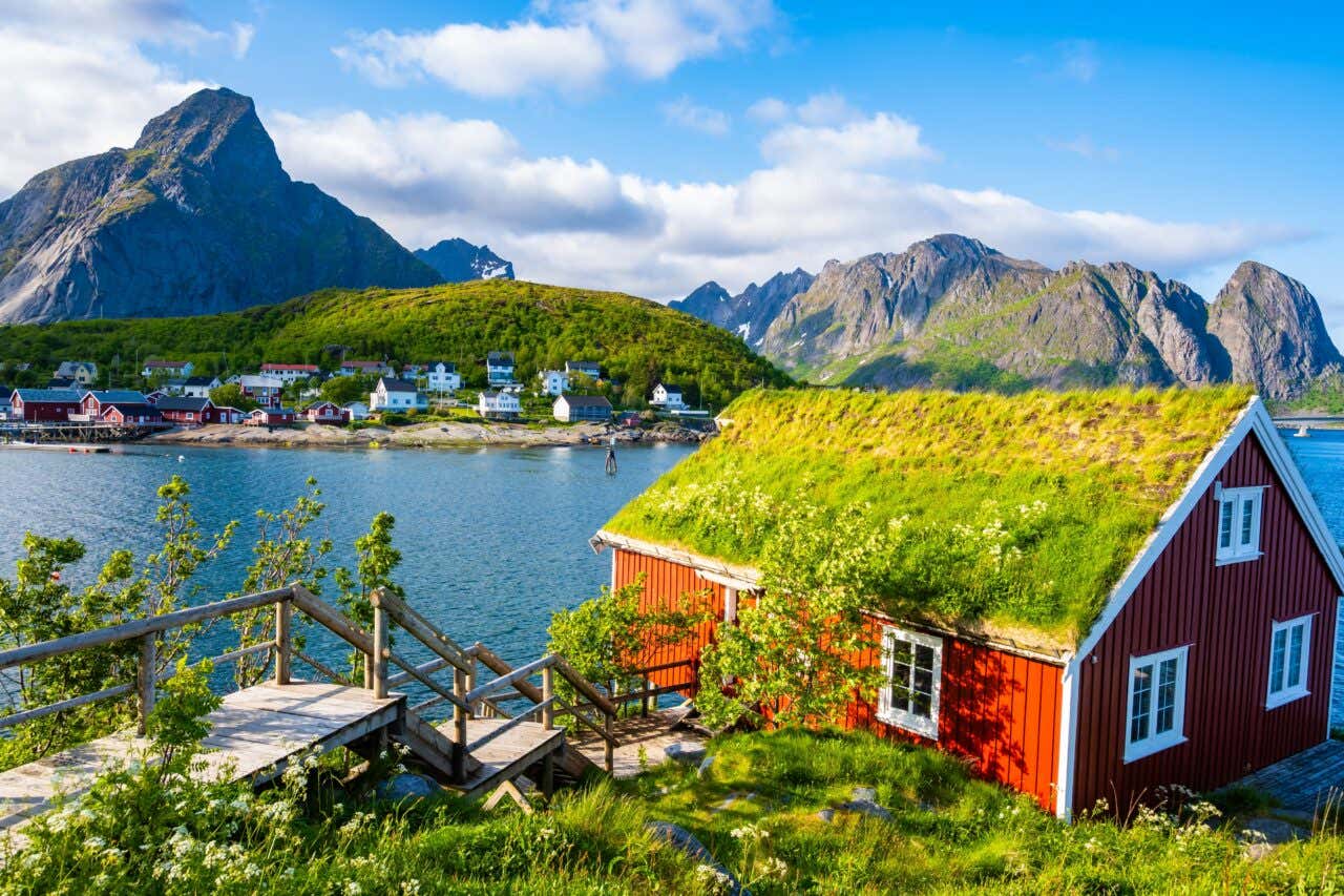 Fjord norvégien avec une maison rouge au toit couvert de végétation au premier plan