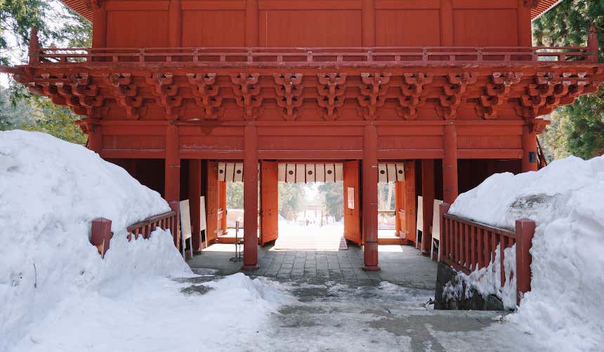 Fachada de templo budista de color rojo en Aomori junto a una espesa capa de nieve.
