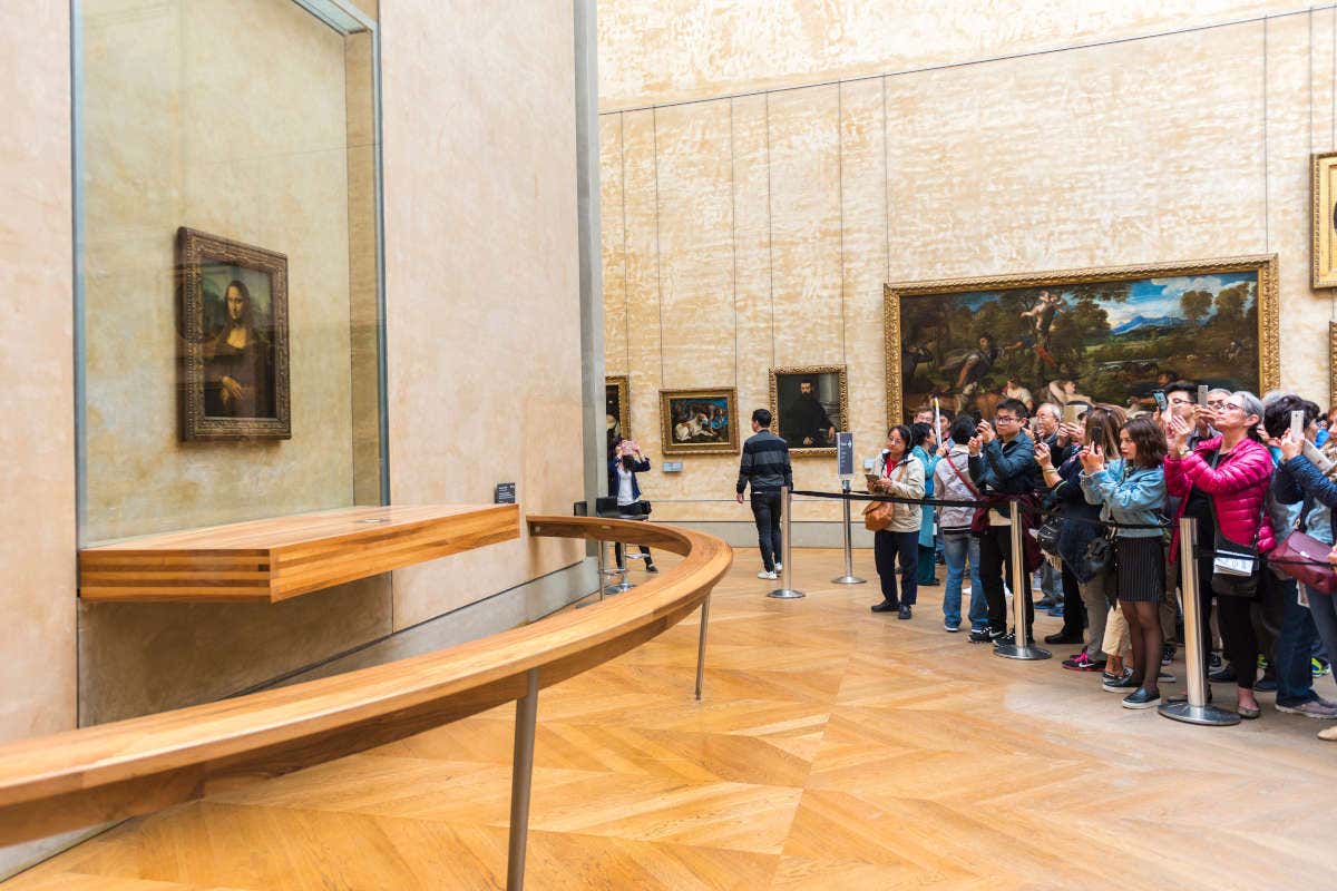 De nombreux touristes en train de photographier de loin la Joconde au Musée du Louvre
