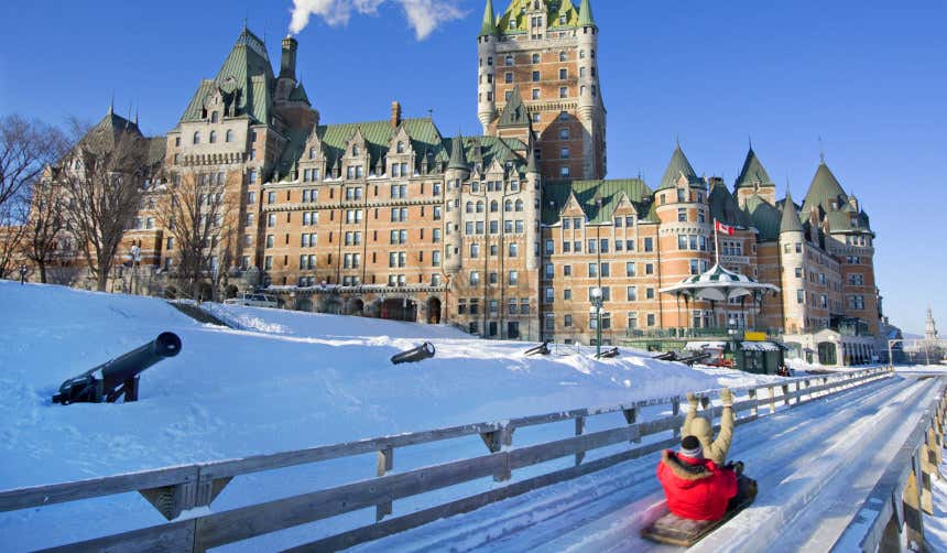 Dos personas se lanzan en trineo por la nieve junto a uno de los edificios más emblemáticos de Quebec