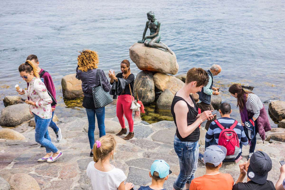 Des touristes en train de se photographier avec la Petite Sirène de Copenhague
