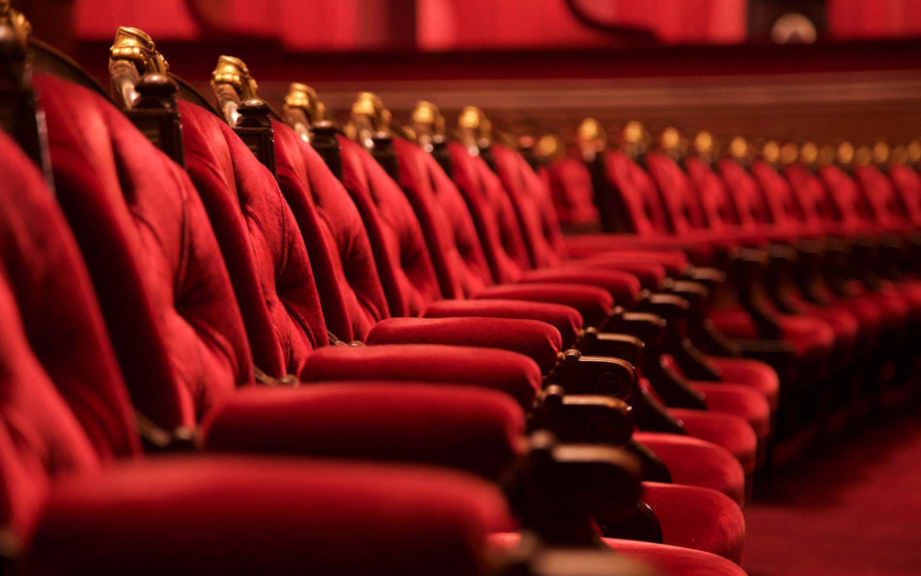 Fila de butacas de un teatro tapizadas de color rojo.
