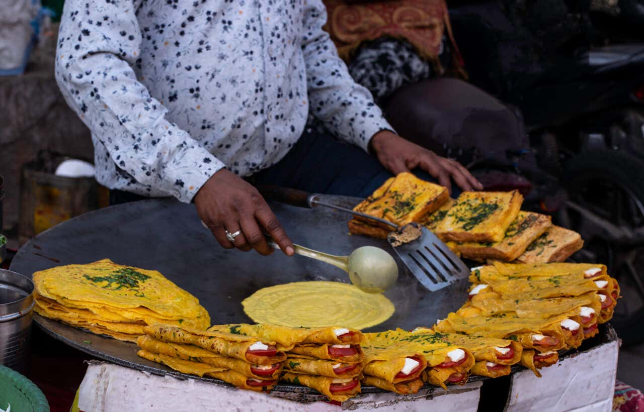 Personne préparant des crêpes garnies à un stand de street food à New Delhi