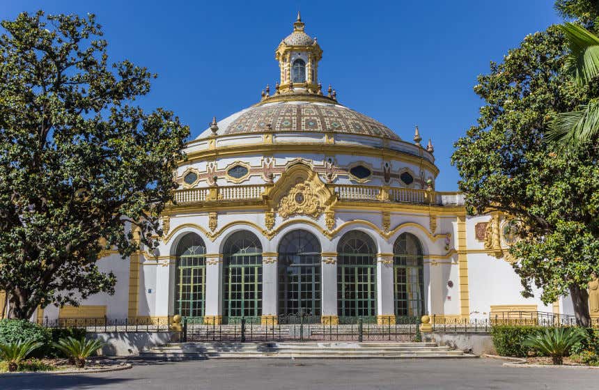 El teatro Lope de Vega de Sevilla, ubicado junto al histórico parque de María Luisa. Vista de su fachada blanca y amarilla y con una cúpula decorada por mosaicos.