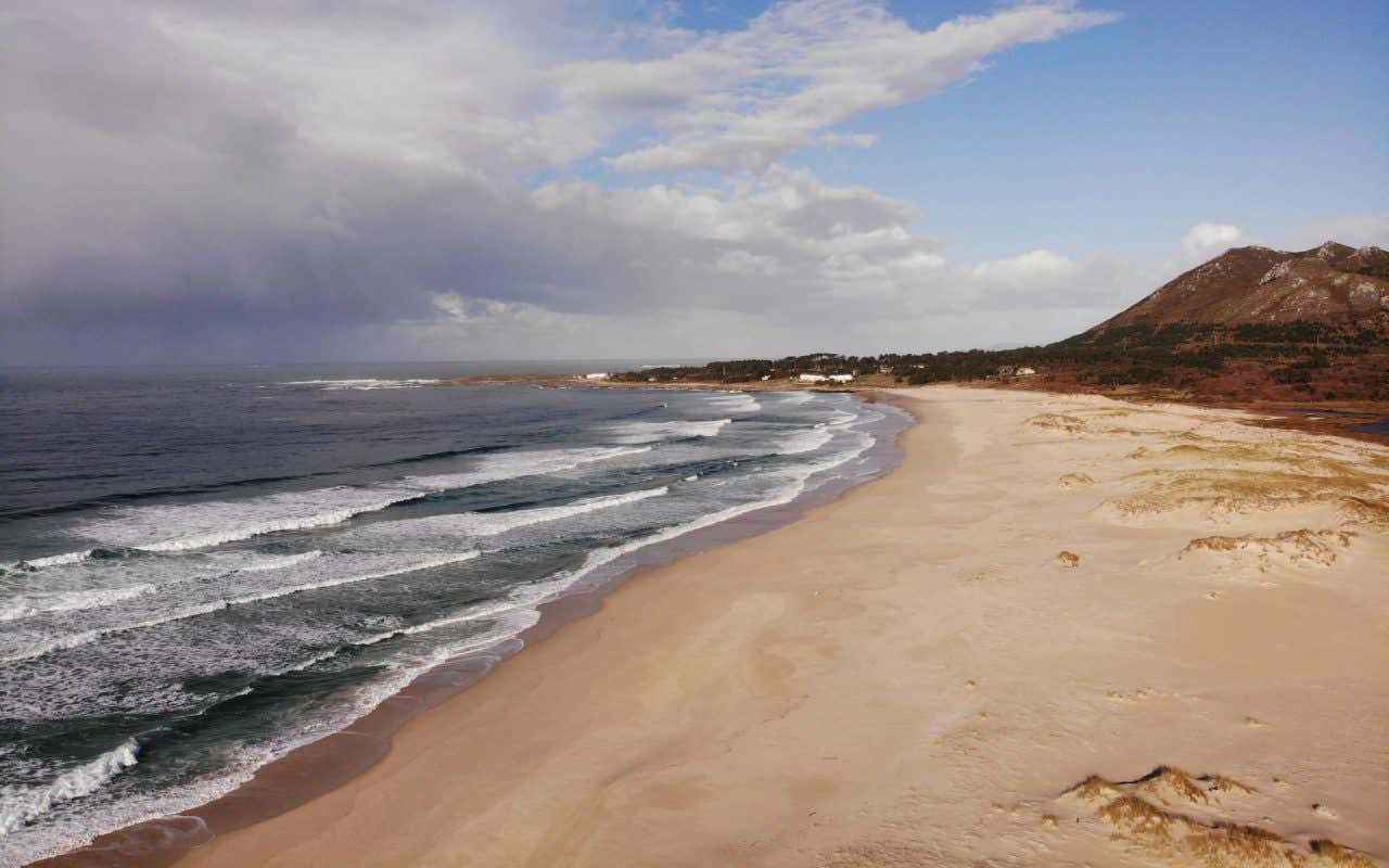 Faixa de areia entre o mar e uma barreira de dunas em Area Maior