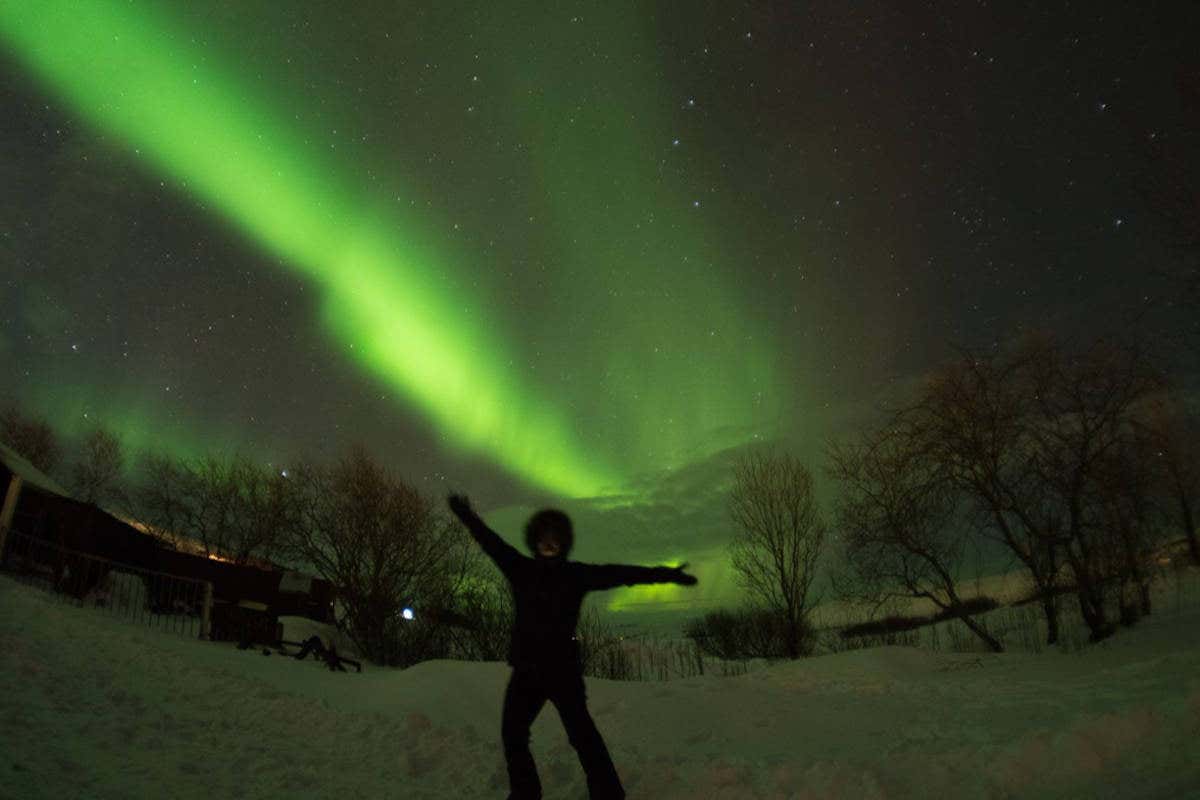 Posando junto a una aurora boreal verde