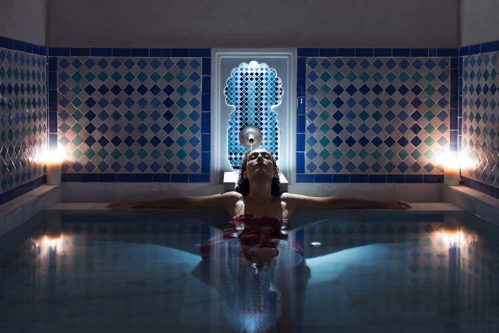 Uma mulher relaxando em uma piscina de um hammam tradicional