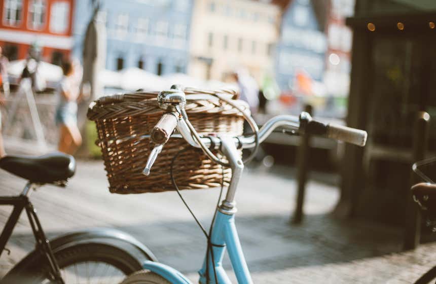 Una bicicleta con su cesta, frente a las coloridas casa del centro de Copenhague.