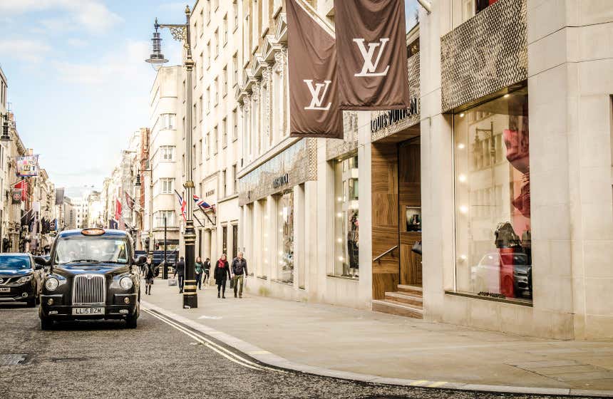 Un taxi de color negro, típicamente inglés, espera junto a una tienda de Louis Vuitton en la calle Bond Street de Londres.