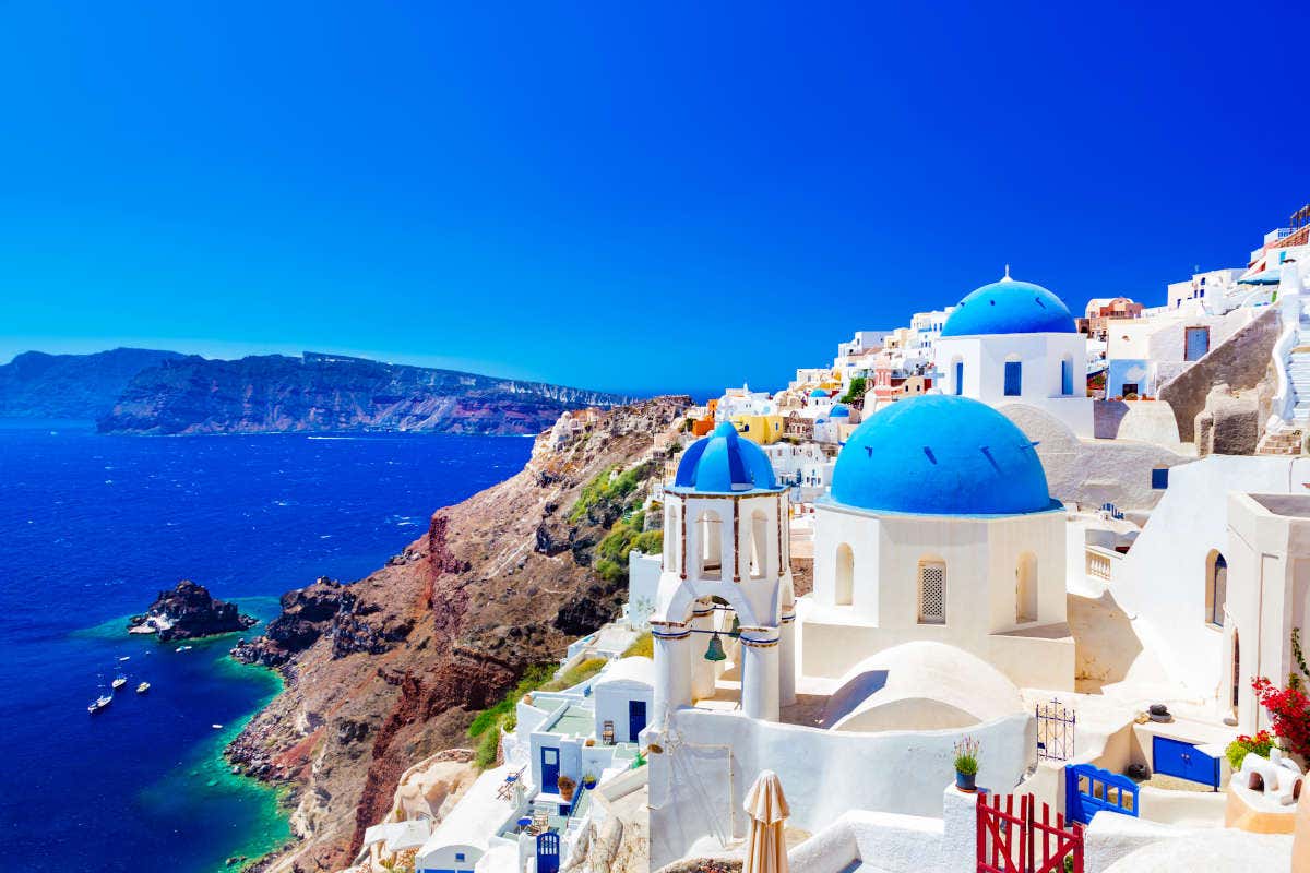 Típica vista de Oia, Santorini, com casas brancas, telhados azuis e os desfiladeiros