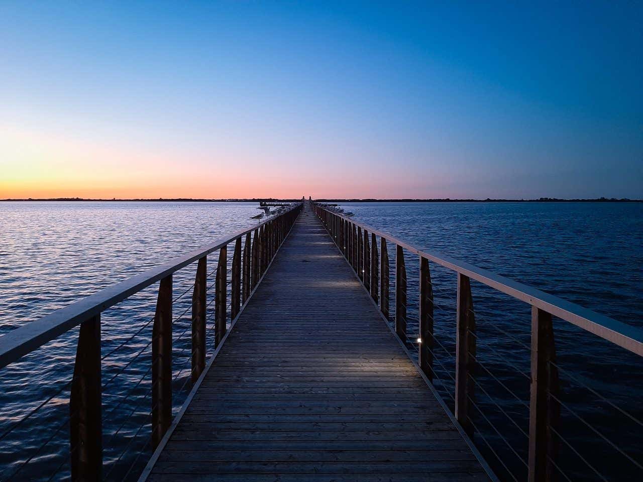 Passerella in legno con gabbiani appollaiati sui cornicioni del lago di Lesina, uno dei laghi più belli d'Italia, in pieno Parco Nazionale del Gargano.