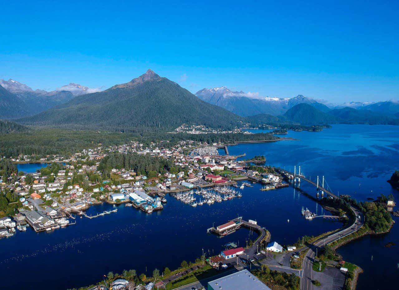Aerial panoramic view of a large tree covered mountain towering over Sitka a small seaside town, one of the many things to do and see in Alaska