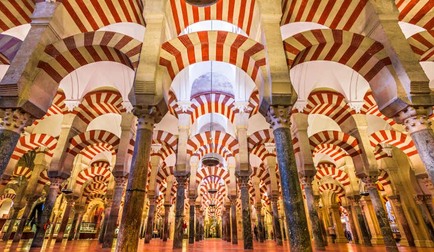 A large hall with lots of columns and red and white arches in the Mosque-Cathedral in Córdoba