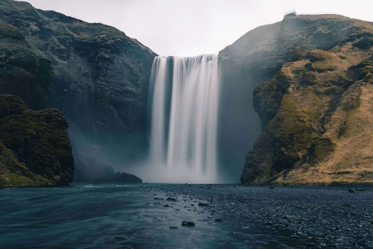 Kontras de la arena negra con el salto de agua
