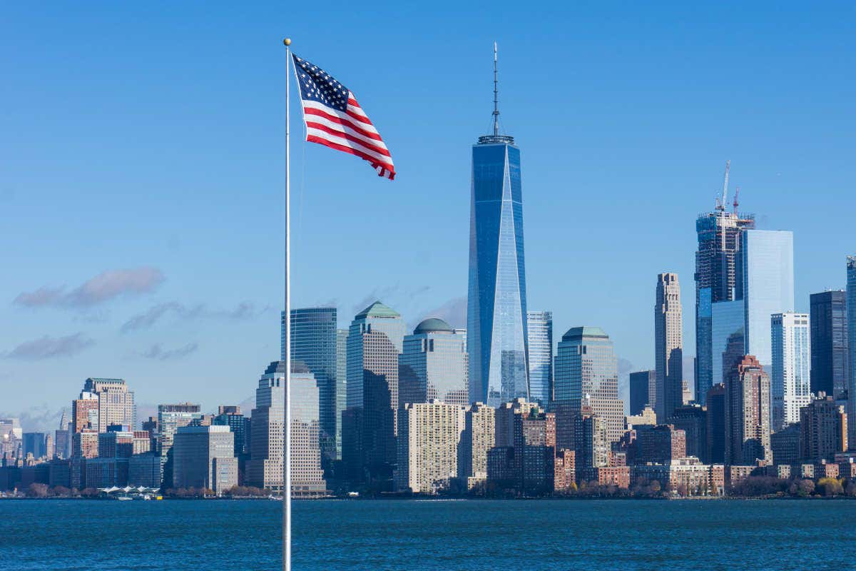 Panorámica de Nueva York con la bandera de Estados Unidos en primer plano y los rascacielos de Manhattan al fondo