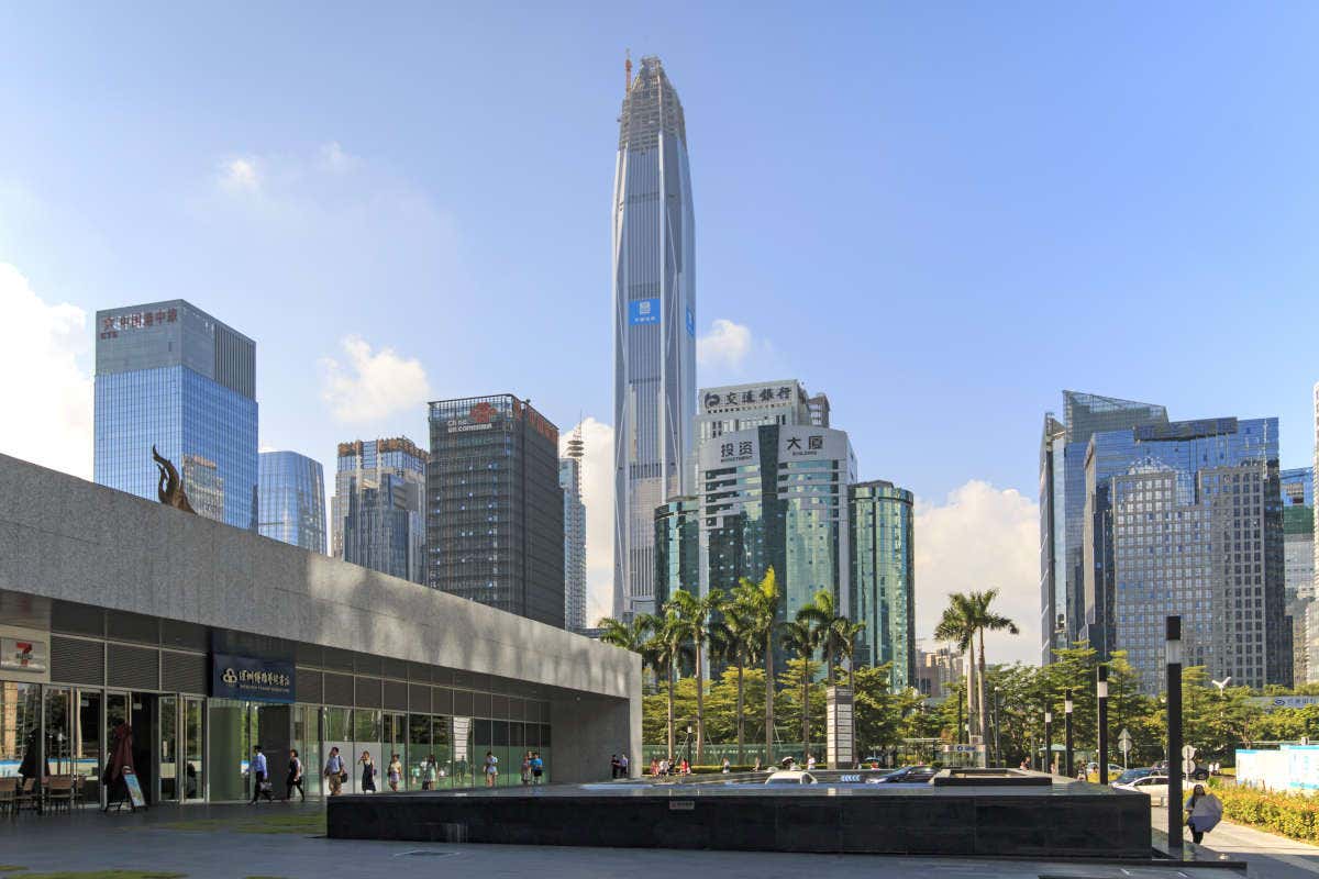 Panorámica de Ping An Finance Center, un rascacielos con altas columnas en sus esquinas y frente a un conjunto de palmeras