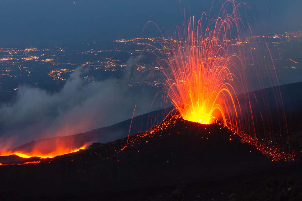 Vista nocturna del monte Etna en erupción expulsando gran cantidad de lava cerca de Catania