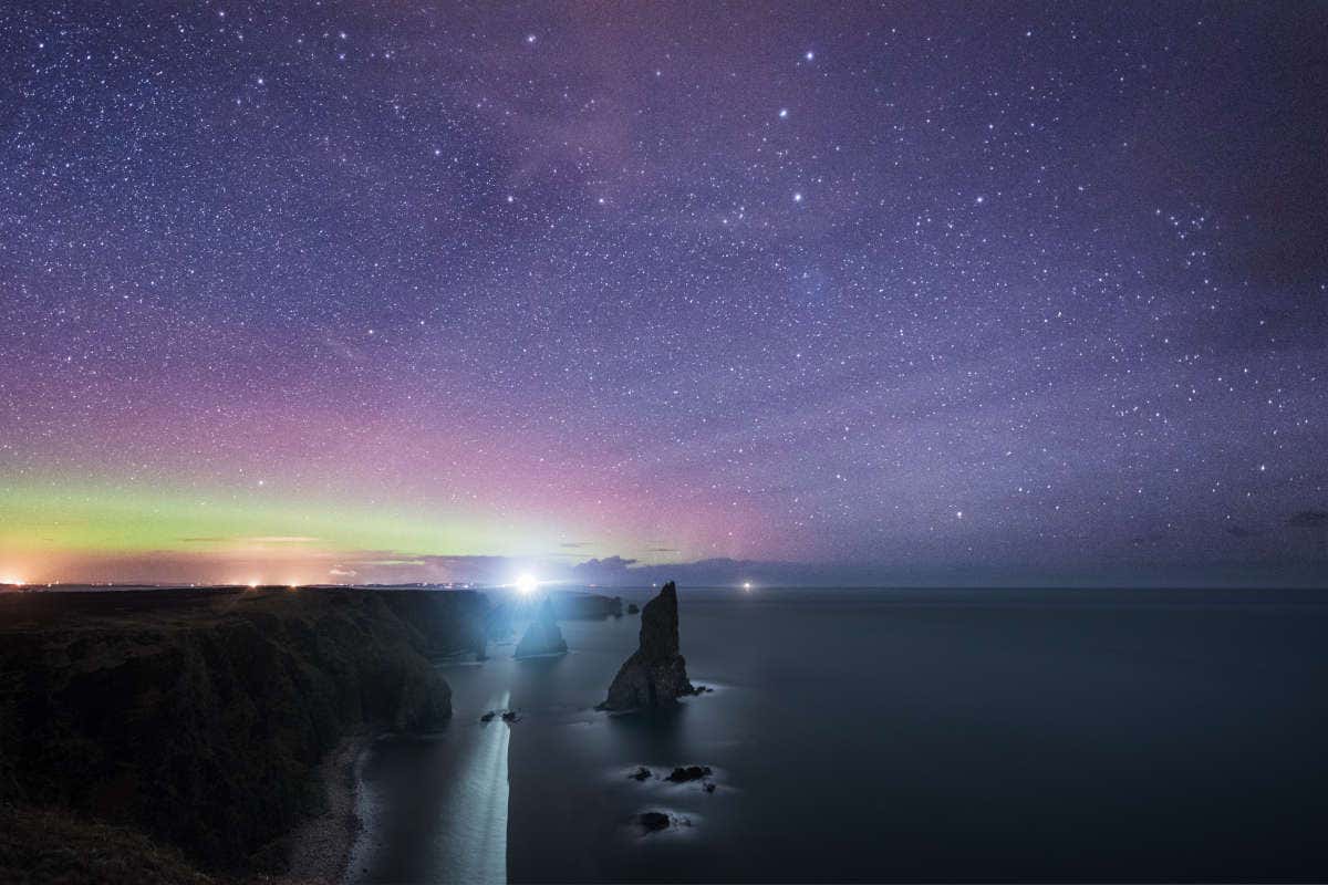 Paisaje escocés bajo el cielo estrellado en tonos morados