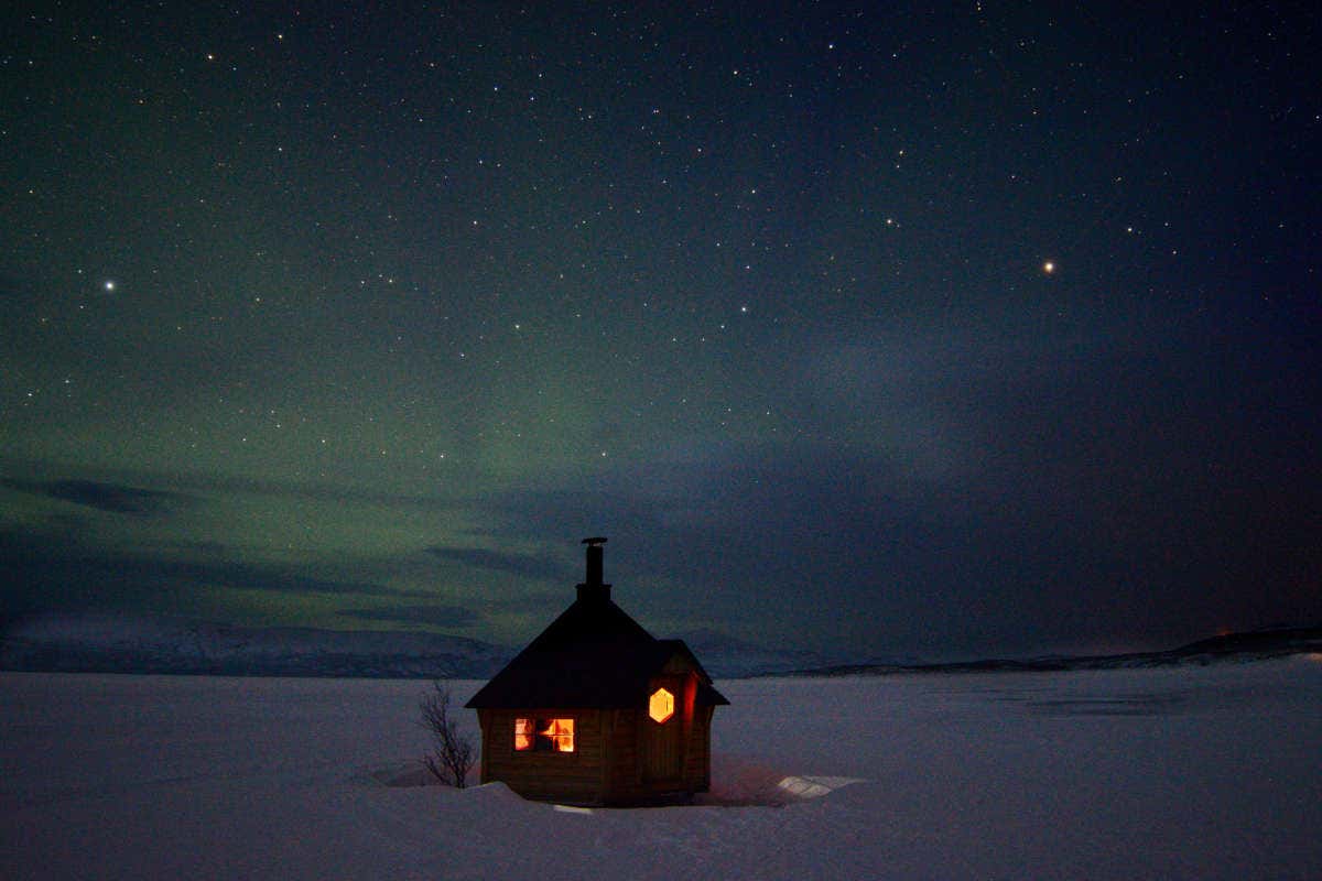 Una casa en el paisaje helado de Kiruna bajo la aurora boreal