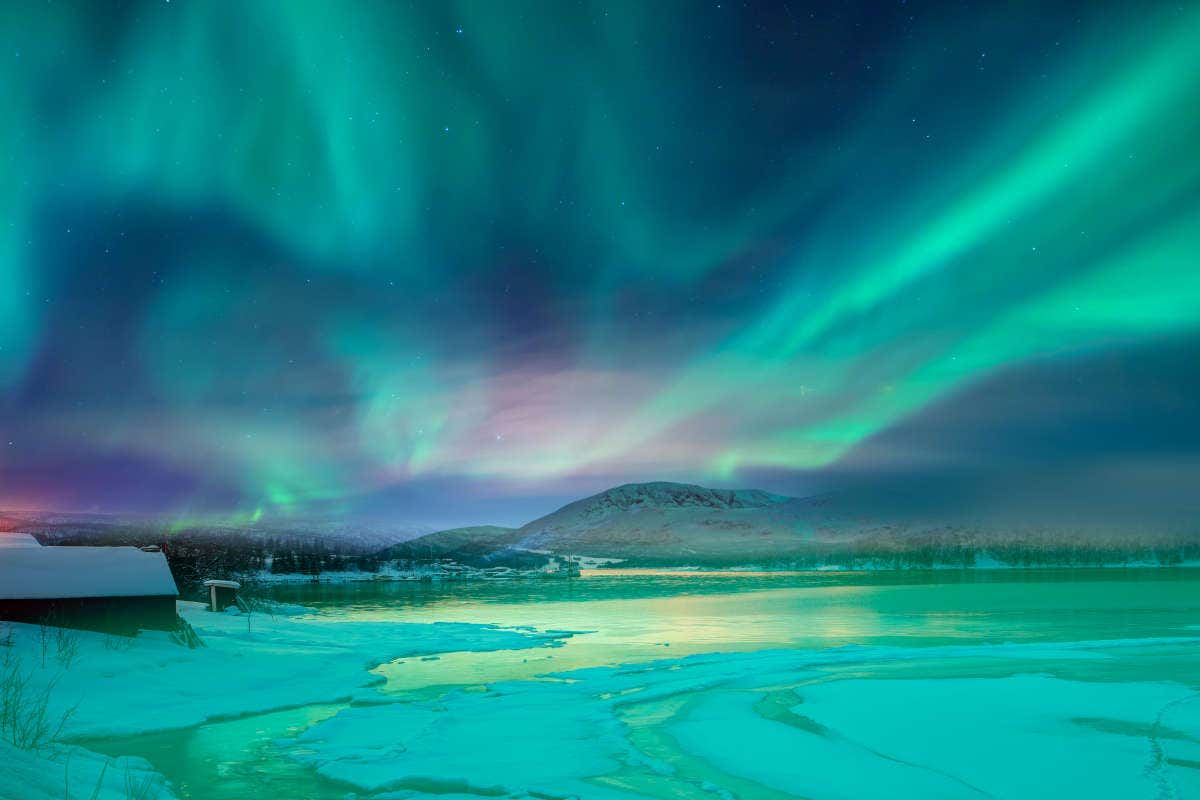 Luces verdes, azules y rosas de la aurora boreal sobre el paisaje helado de Tromsø