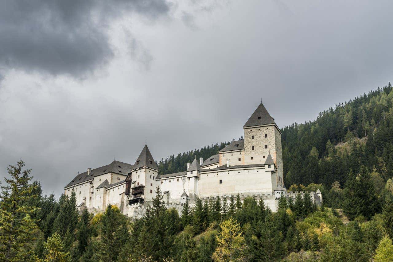 Le Château Moosham au milieu de la forêt et sous un ciel gris et nuageux