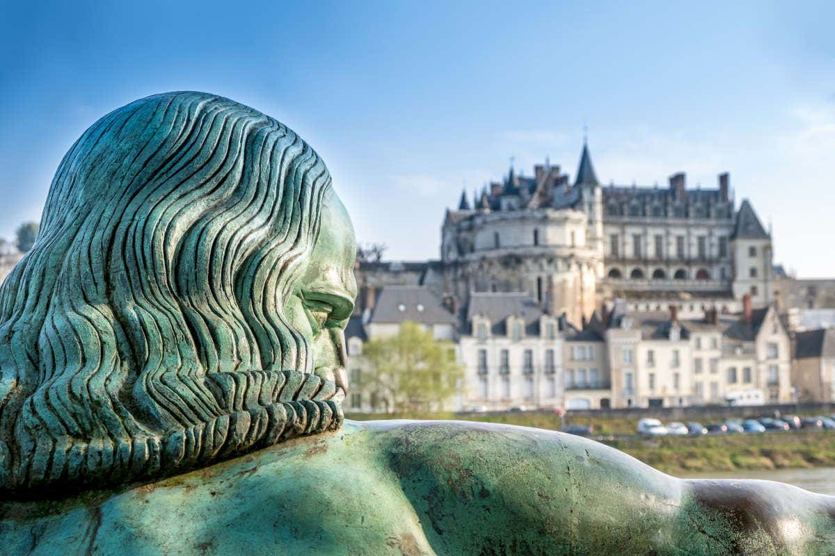 Primeiro plano da escultura de Leonardo da Vinci e o Castelo de Amboise ao fundo.