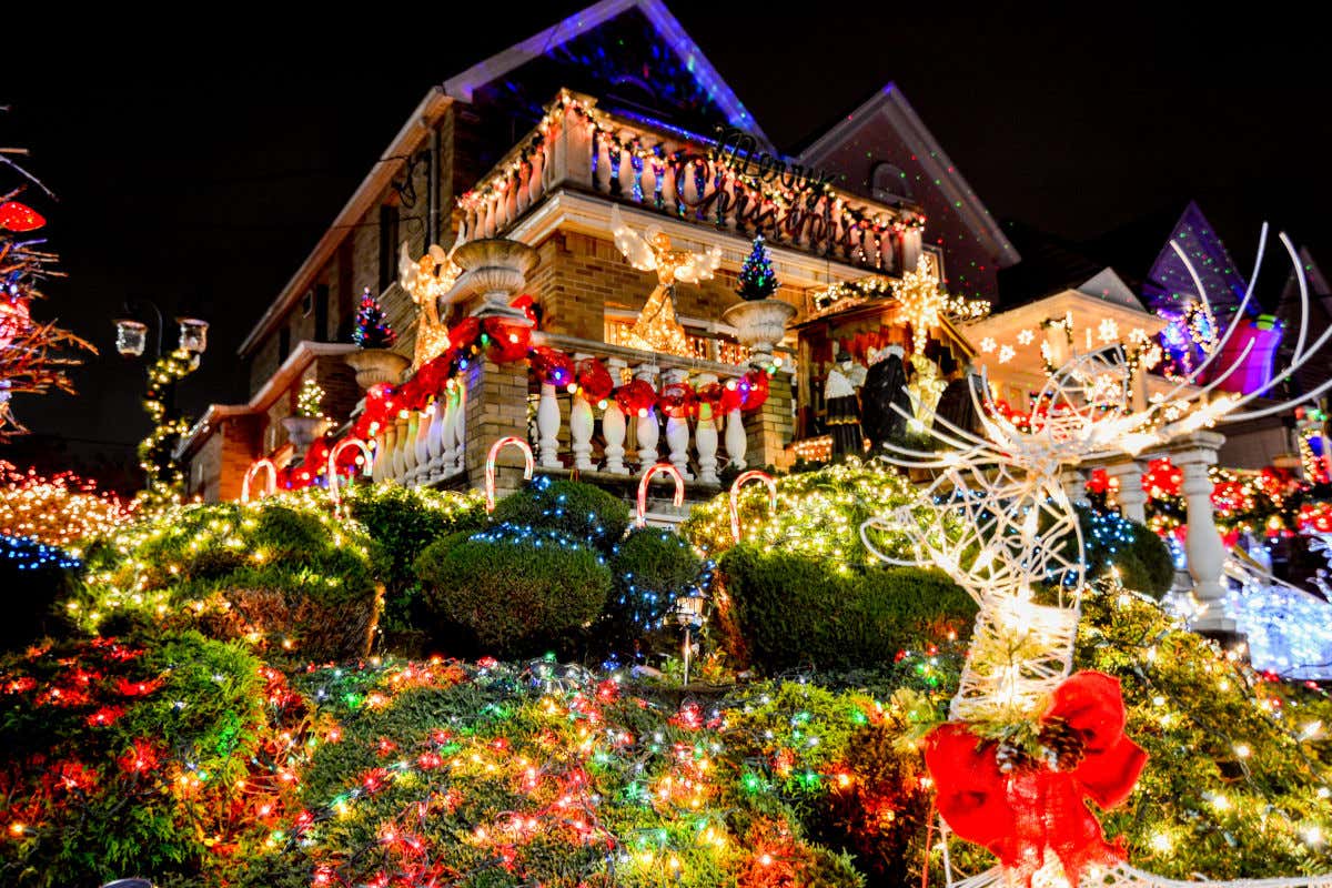 Decoración navideña en los exteriores de una casa y su jardín en el barrio de Dyker Heights. Se pueden ver cientos de luces, una escultura de un reno y varios ángeles