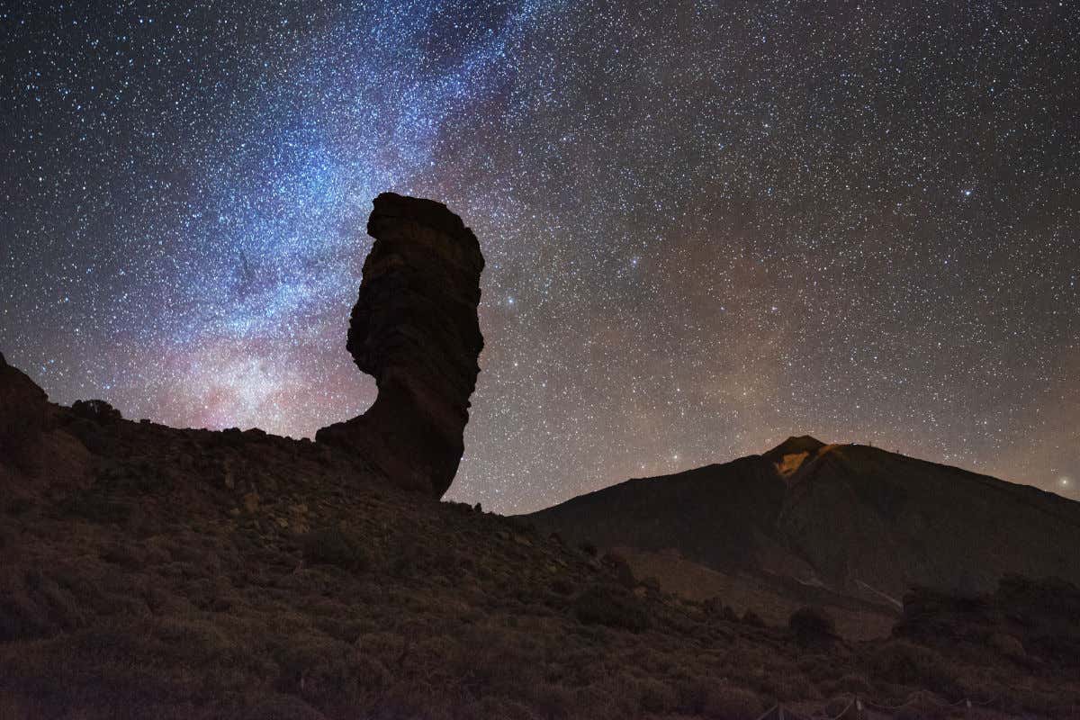 Uno de los brazos de la Vía Láctea junto a la silueta de los roques de García y el volcán del Teide ante un cielo nocturno totalmente estrellado.