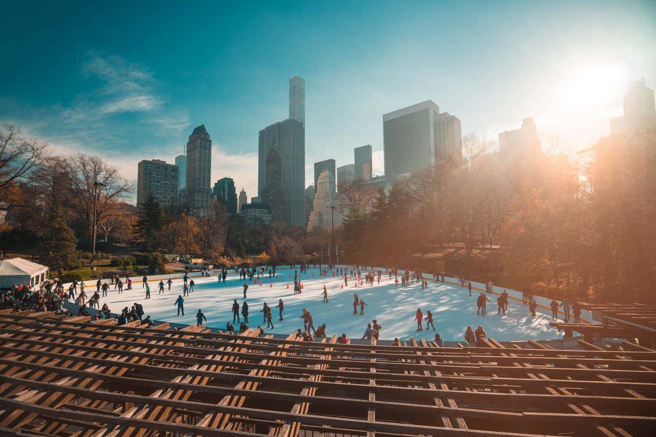Wollman Skating Rink in New York City filled with people ice skating in the middle of the big apple, on a clear winter's day.