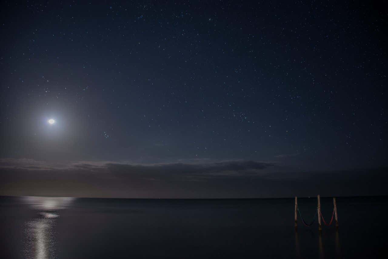 Vista nocturna del cielo estrellado reflejándose en el mar Caribe, en la isla de Holbox