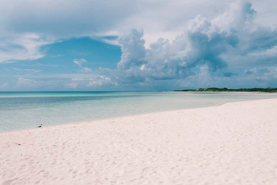Praia Flamencos, com areia branca e água transparente, em um dia nublado