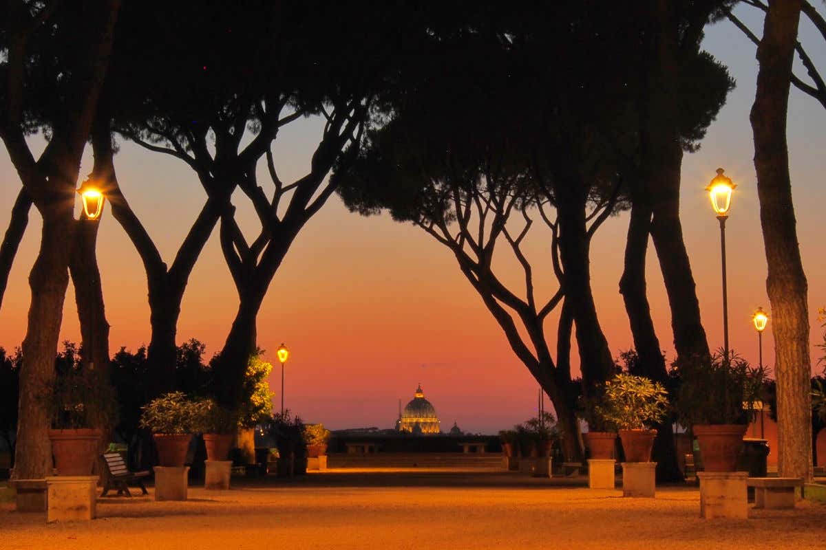 Atardecer en el jardín de los naranjos en Roma con la cúpula de la basílica de San Pedro iluminada en la lejanía.