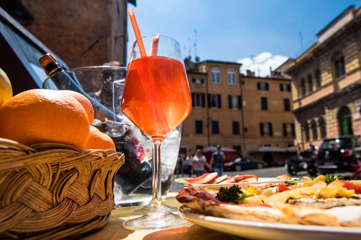 Una copa de aperol spritz y una pizza en la plaza de Santa María en Trastevere
