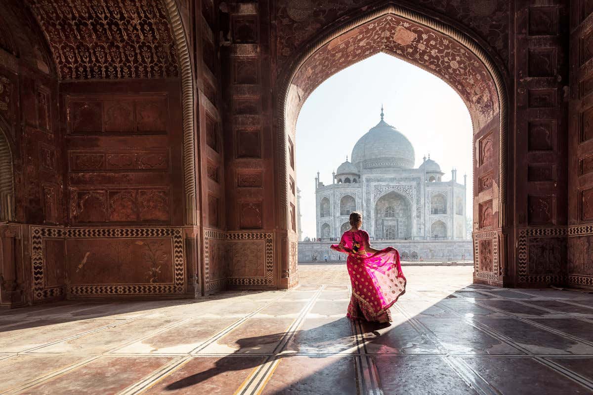 Uma mulher vestida de rosa em frente ao Taj Mahal