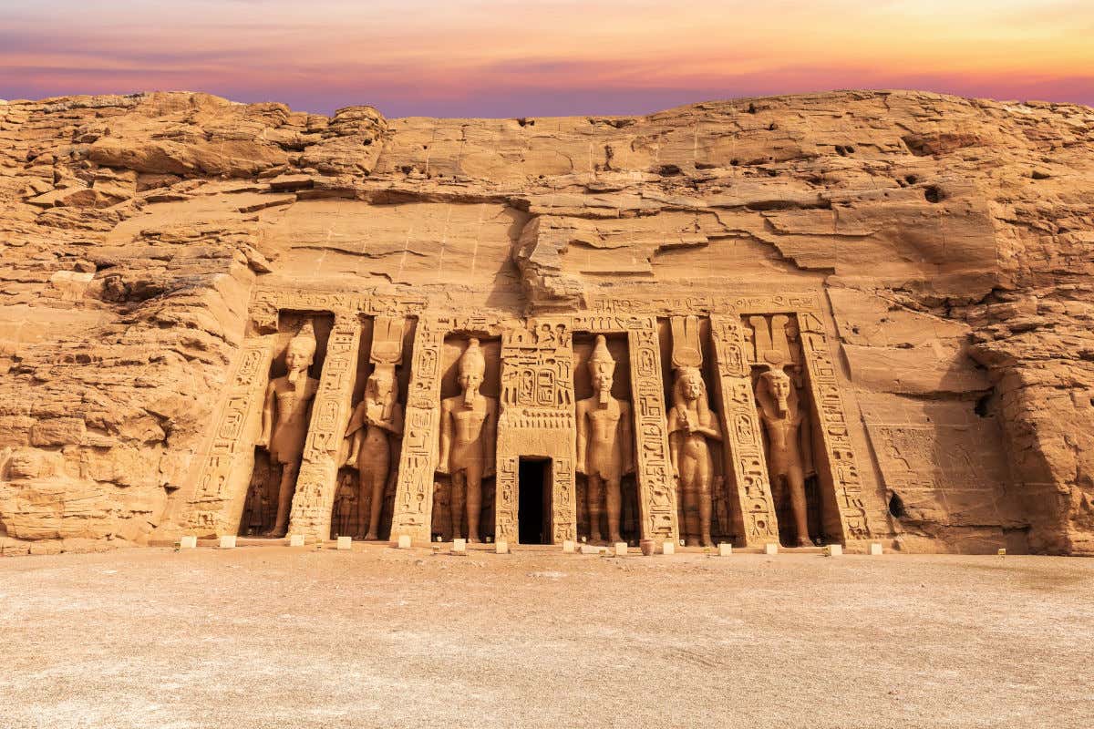 Enormes esculturas de pedra escavadas na rocha na entrada del templo do Nefertari, em Abu Simbel